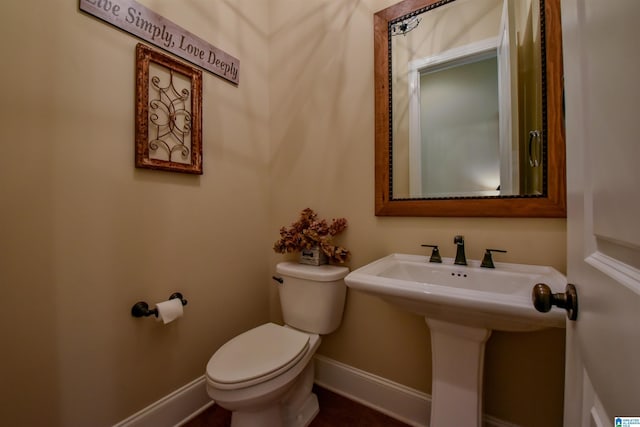 half bath featuring toilet, baseboards, and a sink