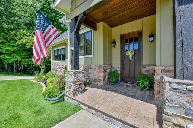 property entrance with a porch, stone siding, a lawn, and board and batten siding