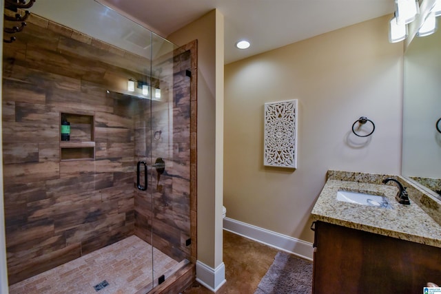 bathroom with toilet, a stall shower, vanity, and baseboards