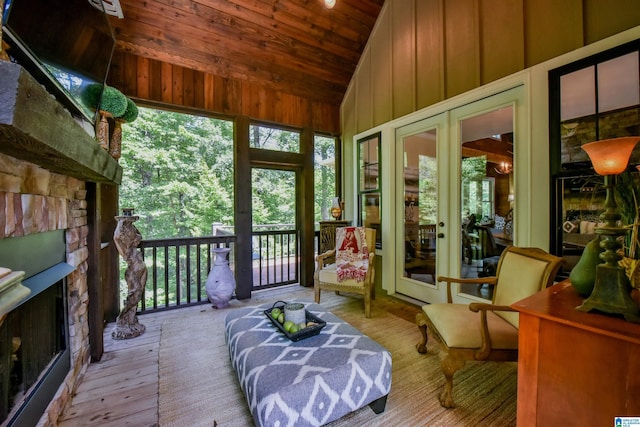 sunroom with wood ceiling, french doors, a stone fireplace, and vaulted ceiling