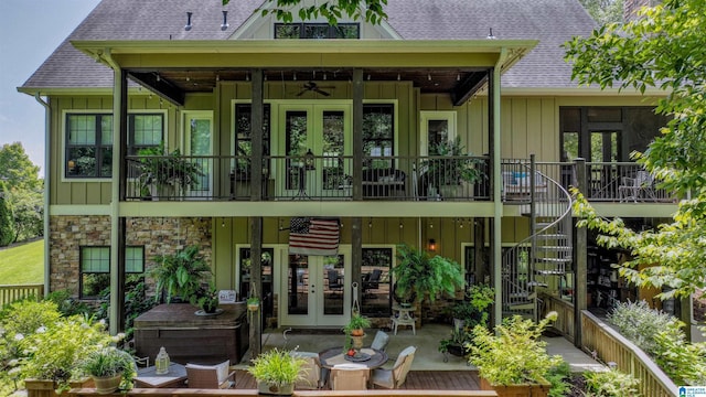 back of property featuring a shingled roof, stairs, french doors, stone siding, and board and batten siding