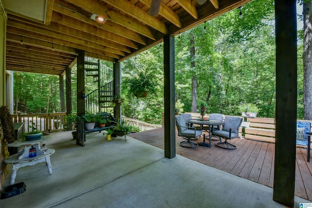 view of patio featuring outdoor dining space, stairway, and a deck