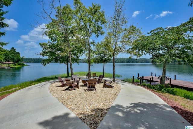 exterior space with a dock, a water view, and an outdoor fire pit