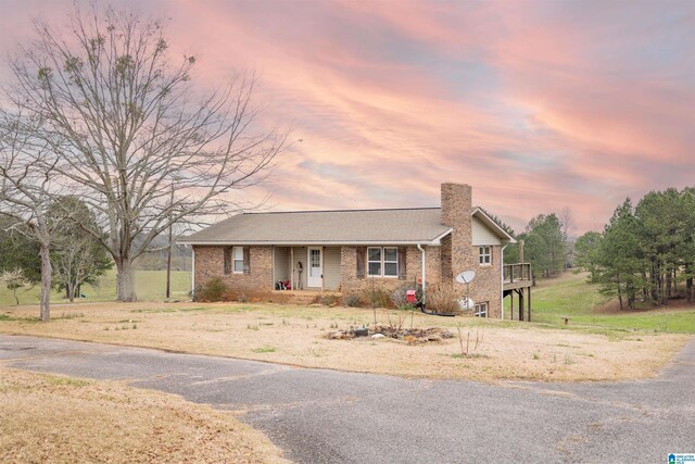 view of front of property featuring brick siding, a porch, and a chimney