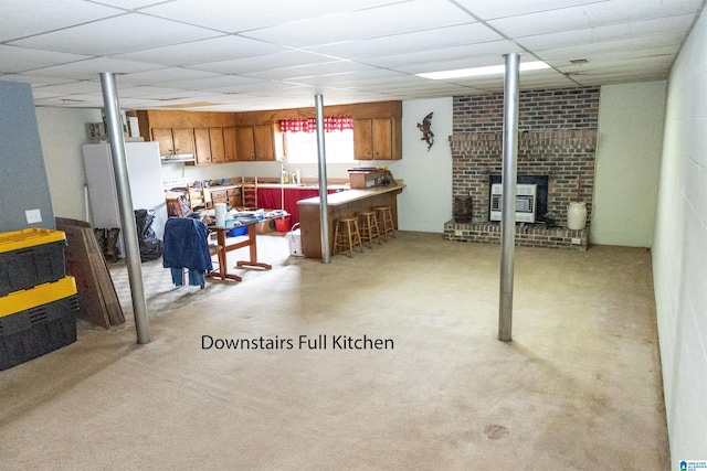 below grade area featuring bar area, heating unit, light colored carpet, and a drop ceiling