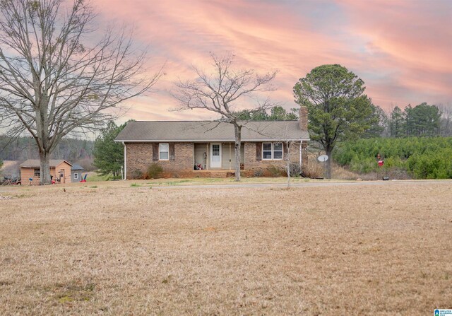 view of front of house featuring a front yard, brick siding, and a chimney