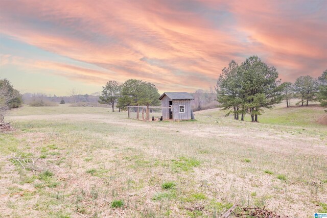 yard at dusk with an outbuilding, a rural view, and a storage shed