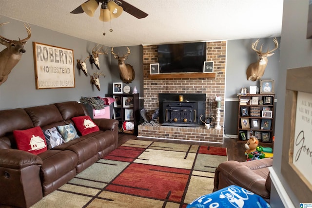 living room featuring a ceiling fan, wood finished floors, a fireplace, and a textured ceiling