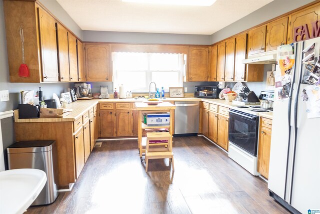 kitchen featuring under cabinet range hood, dark wood-style floors, white appliances, brown cabinetry, and light countertops