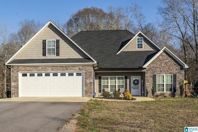 craftsman inspired home featuring stone siding, a front yard, driveway, and a shingled roof