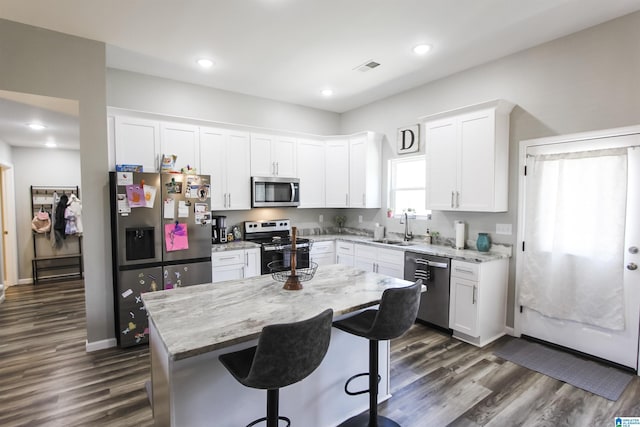 kitchen featuring white cabinets, light stone countertops, stainless steel appliances, and a sink