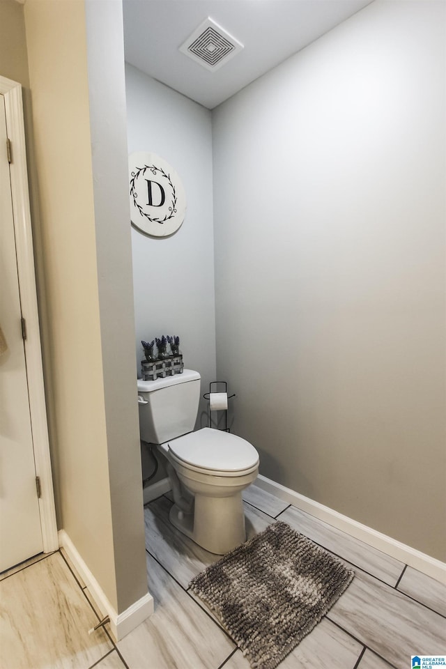 bathroom featuring visible vents, toilet, baseboards, and wood finished floors