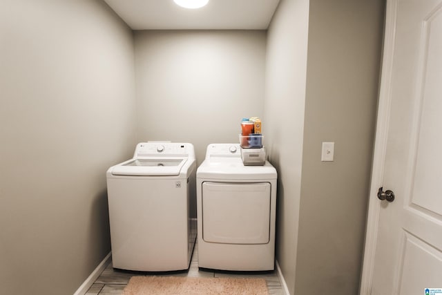 clothes washing area featuring baseboards, washing machine and dryer, and laundry area