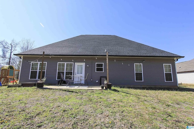 rear view of property with a playground, a yard, a patio area, and roof with shingles