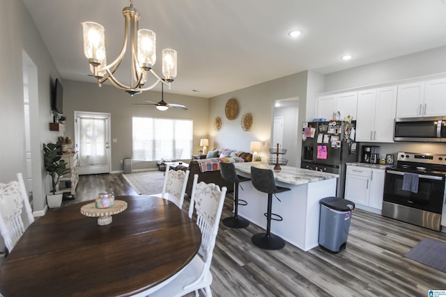 dining room with ceiling fan with notable chandelier, dark wood-type flooring, recessed lighting, and baseboards