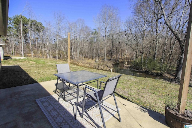 view of patio with outdoor dining space and a forest view