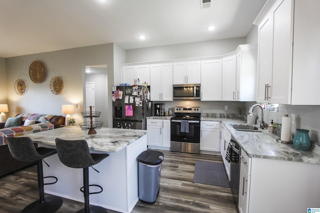 kitchen featuring light stone countertops, appliances with stainless steel finishes, white cabinetry, and a sink