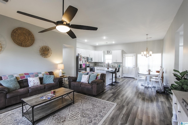 living room with visible vents, recessed lighting, ceiling fan with notable chandelier, and dark wood-style flooring