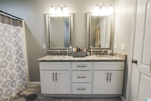 full bathroom featuring double vanity, baseboards, and a sink