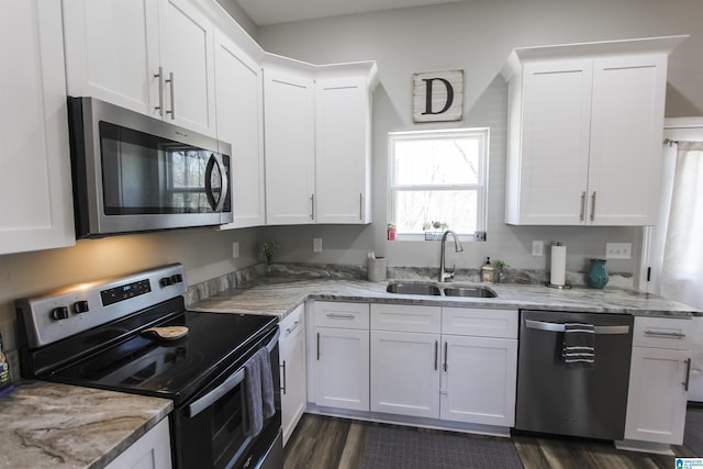 kitchen with a sink, stainless steel appliances, light stone counters, and white cabinetry