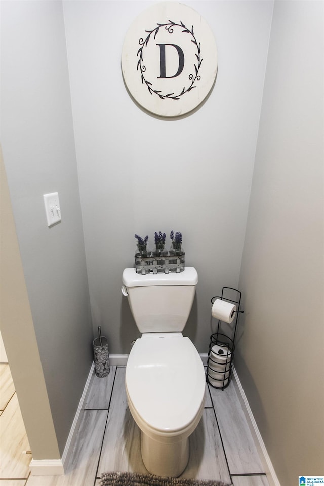 bathroom featuring toilet, baseboards, and wood finished floors