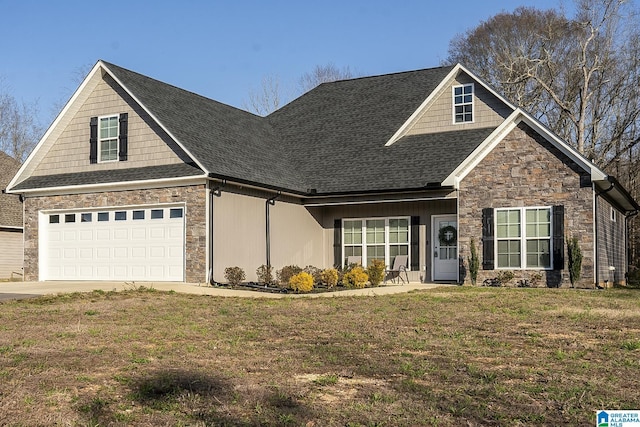 craftsman-style home featuring a garage, a shingled roof, a front yard, and stone siding