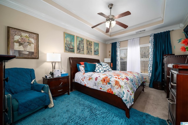 bedroom with visible vents, ceiling fan, a tray ceiling, ornamental molding, and carpet flooring