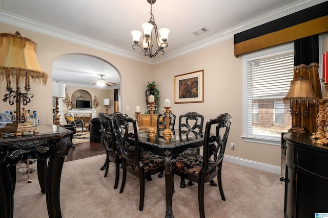 dining space featuring visible vents, baseboards, arched walkways, crown molding, and light colored carpet