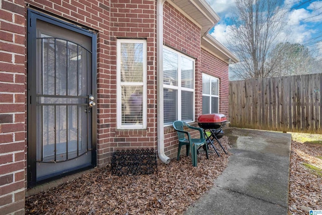 property entrance featuring fence and brick siding