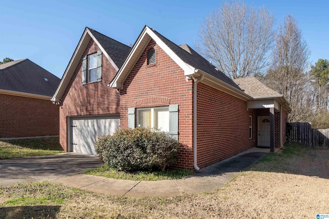 view of property exterior with brick siding, a shingled roof, concrete driveway, and fence