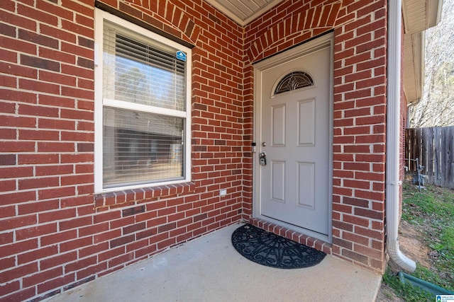 property entrance featuring brick siding and fence