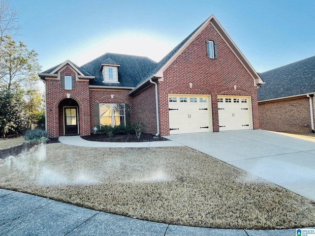 traditional-style home with brick siding, a garage, concrete driveway, and roof with shingles