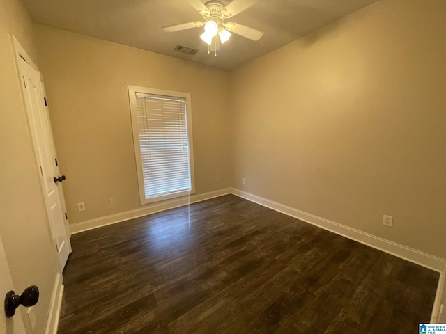 empty room with dark wood finished floors, visible vents, ceiling fan, and baseboards