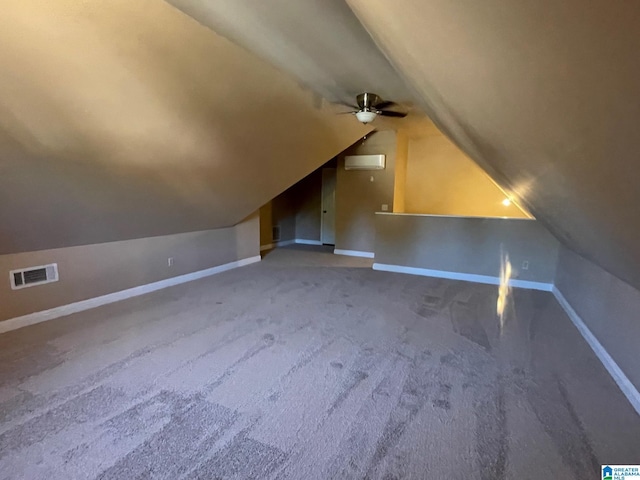 additional living space featuring visible vents, carpet, baseboards, an AC wall unit, and vaulted ceiling