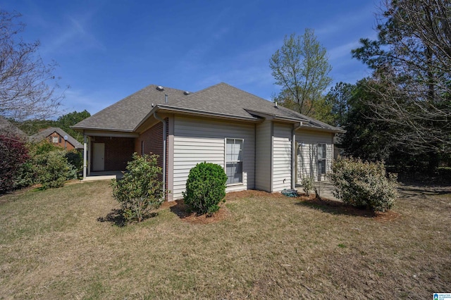 view of home's exterior with a lawn and a shingled roof