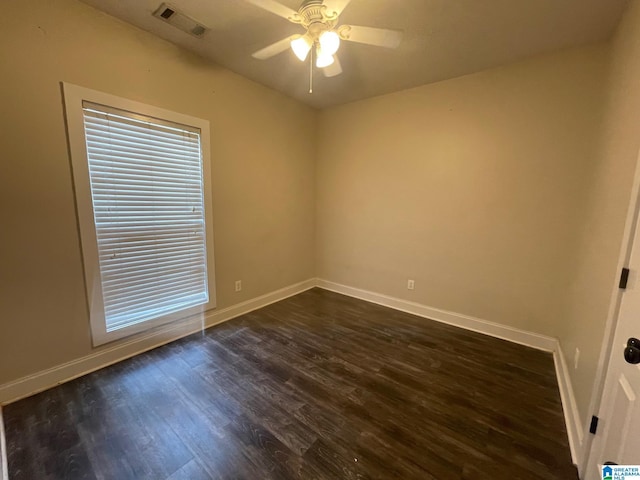 empty room featuring visible vents, baseboards, and dark wood-style flooring