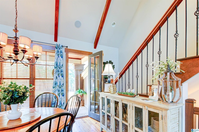 dining space featuring stairway, vaulted ceiling with beams, wood finished floors, and a chandelier