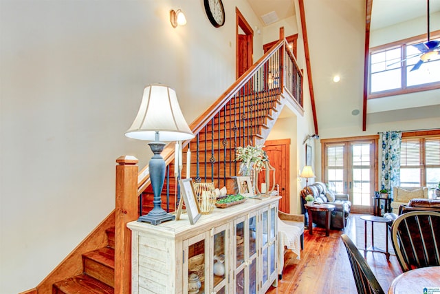 stairway with hardwood / wood-style floors and a towering ceiling