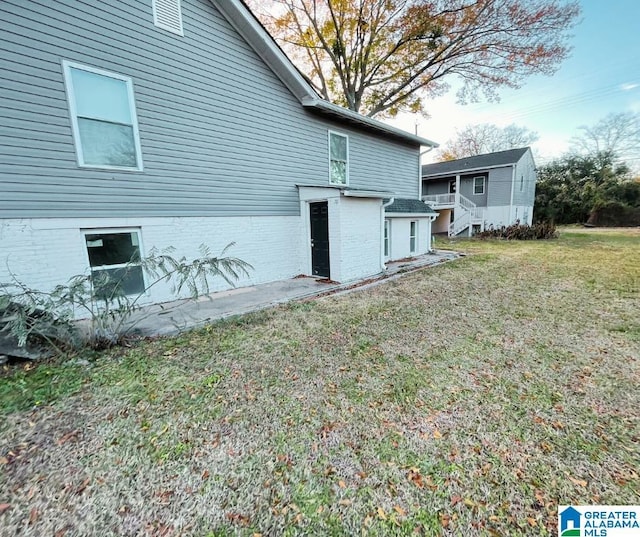 rear view of house featuring a lawn and brick siding