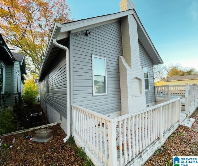 view of side of property featuring crawl space, a chimney, and brick siding