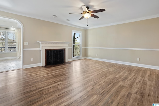 unfurnished living room with wood finished floors, a healthy amount of sunlight, ceiling fan, and ornamental molding