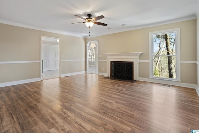 unfurnished living room featuring visible vents, a ceiling fan, wood finished floors, arched walkways, and baseboards