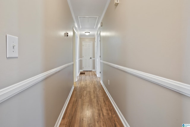 hall with attic access, crown molding, baseboards, and wood finished floors