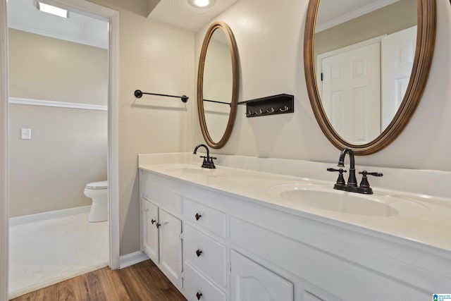 bathroom featuring a sink, toilet, wood finished floors, and double vanity