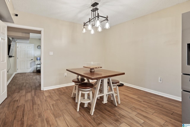 unfurnished dining area featuring an inviting chandelier, wood finished floors, and baseboards