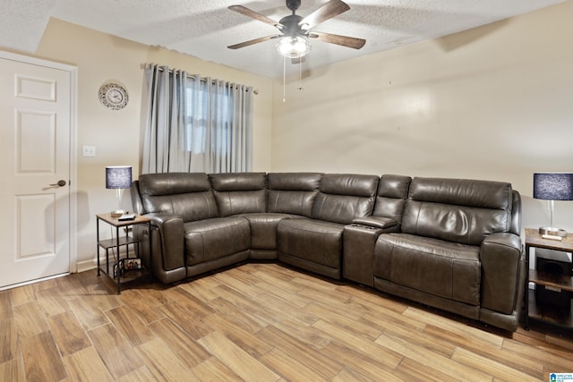 living area with light wood-style floors, ceiling fan, and a textured ceiling