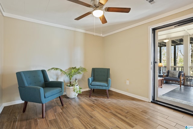 living area with crown molding, wood finished floors, baseboards, and ceiling fan