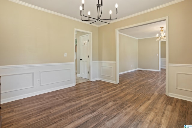 spare room featuring a chandelier, a wainscoted wall, dark wood finished floors, and crown molding