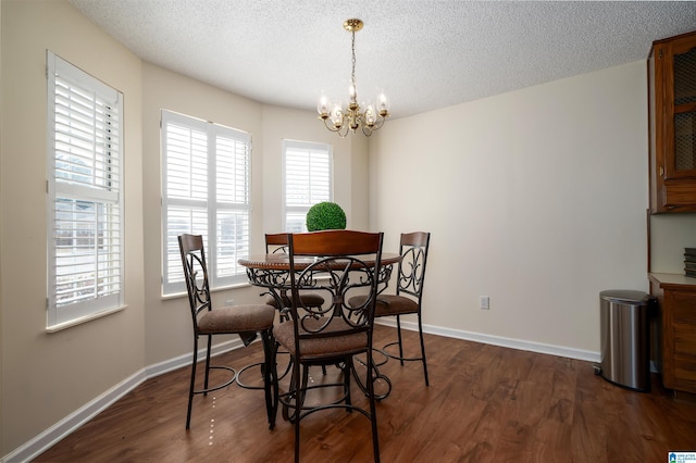 dining room featuring dark wood-style floors, a chandelier, a textured ceiling, and baseboards