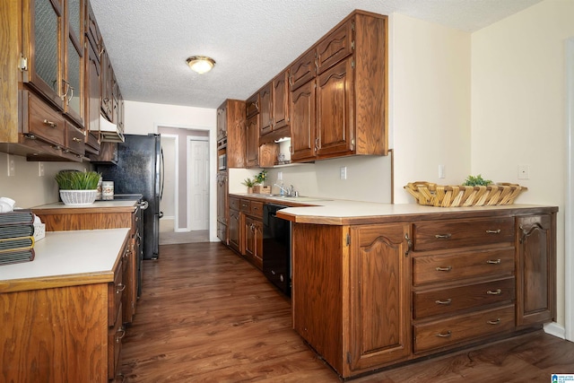 kitchen featuring dark wood-type flooring, light countertops, a peninsula, a textured ceiling, and black appliances